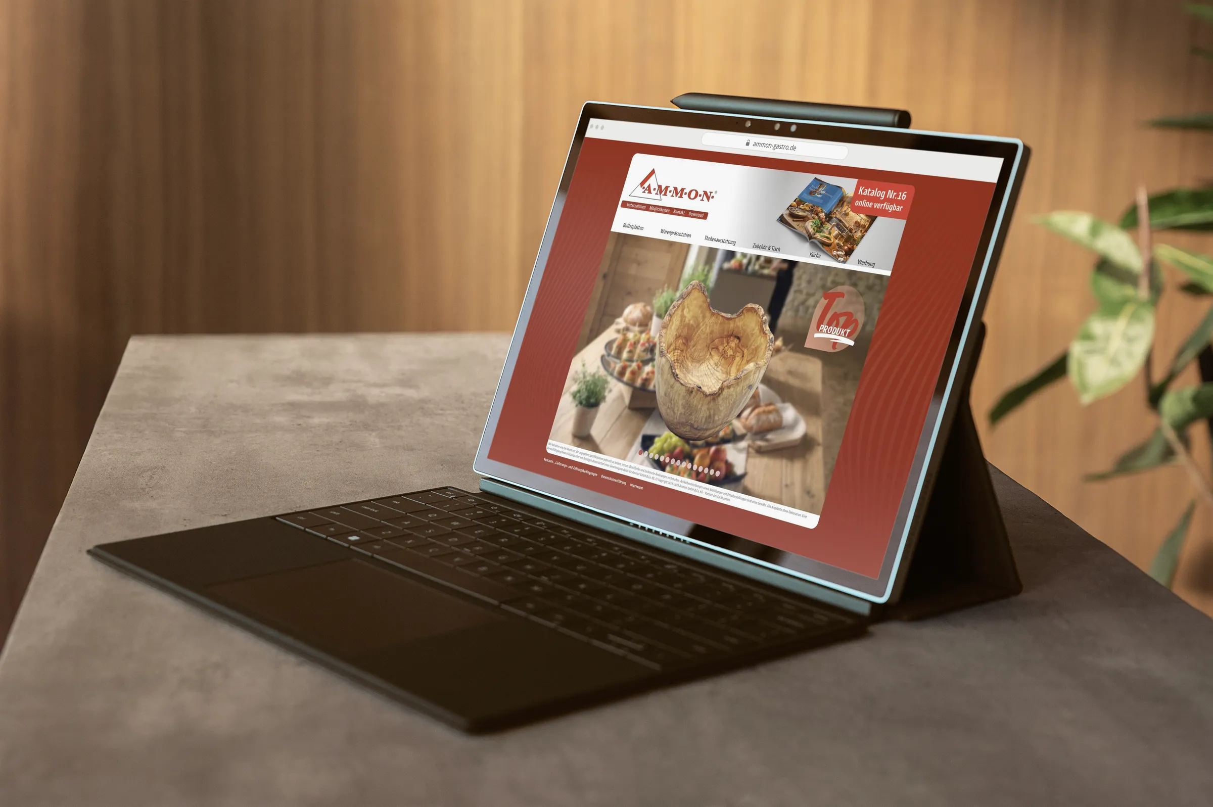 Tablet mit Tastatur auf einem Tisch, auf dem Bildschirm die Startseite von ammon-gastro.de mit einer Schüssel aus Olivenholz als Top-Produkt